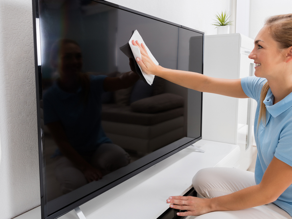 Mujer limpiando una pantalla de TV